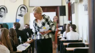 Nauczycielka rozdaje arkusze egzaminacyjne. Co jeśli ktoś umrze podczas egzaminu? Sala pełna uczniów, napięcie w powietrzu.