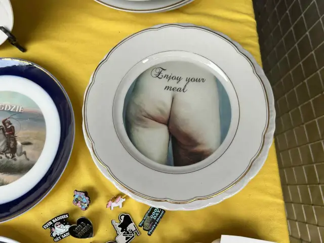 Talerz z napisem "Enjoy your meal" i zdjęciem pośladków. To jest żart, który może wywołać uśmiech lub zdziwienie.
